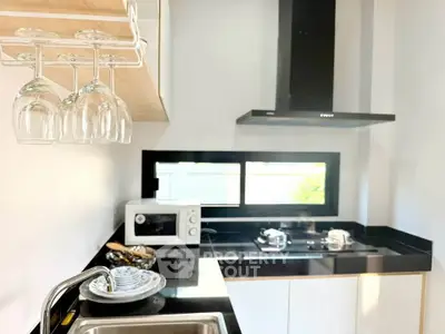 Modern kitchen with sleek black countertops and built-in appliances, featuring a stylish open layout.