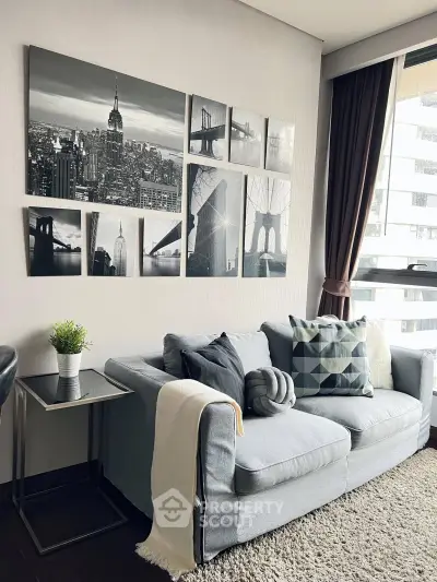 Stylish living room with modern decor and cityscape wall art, featuring a cozy gray sofa and large window.