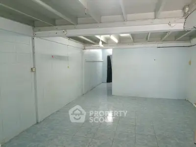 Spacious empty room with tiled floor and exposed ceiling beams, ideal for customization.