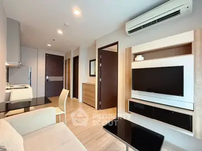 Modern living room with sleek furniture and open kitchen layout, featuring a wall-mounted TV and air conditioning.