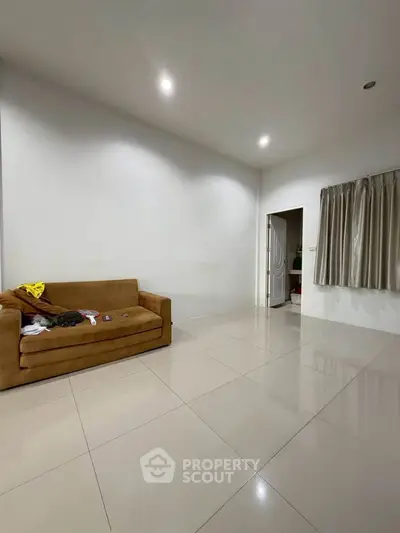 Spacious living room with modern tile flooring and cozy brown sofa, perfect for relaxation and entertainment.