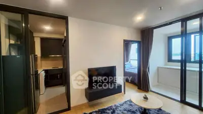 Modern apartment interior with open living room, kitchen, and bedroom view.