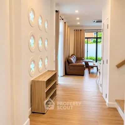 Modern living room with stylish decor and natural light, featuring a cozy leather sofa and elegant wooden flooring.
