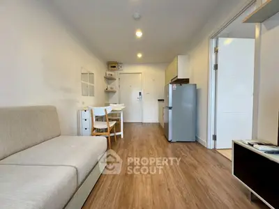 Modern open-plan living room with wooden flooring and compact kitchen area.