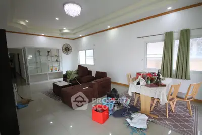 Spacious living room with modern furniture and dining area, featuring elegant lighting and large windows.
