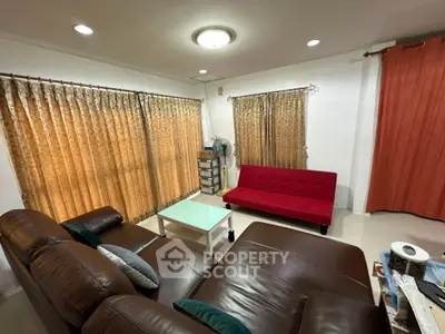Cozy living room with leather sofas and red futon, perfect for relaxation.
