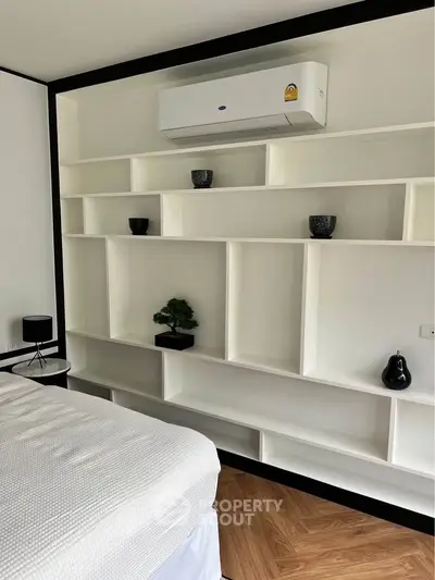Modern bedroom with built-in shelving and air conditioning unit