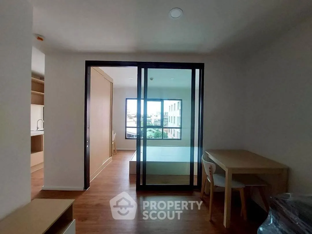 Modern apartment interior with glass partition, wooden flooring, and compact dining area.