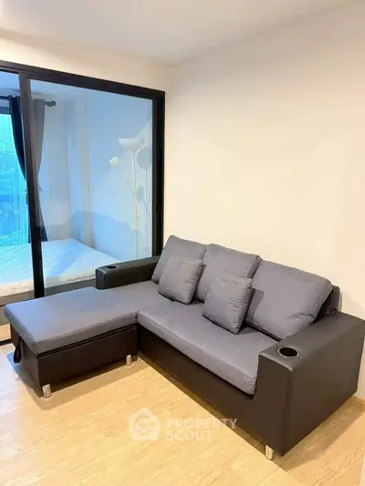 Modern living room with stylish sofa and glass door leading to balcony, perfect for relaxation.