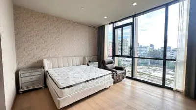 Spacious bedroom with large windows offering a stunning city view, featuring a comfortable bed and elegant decor.