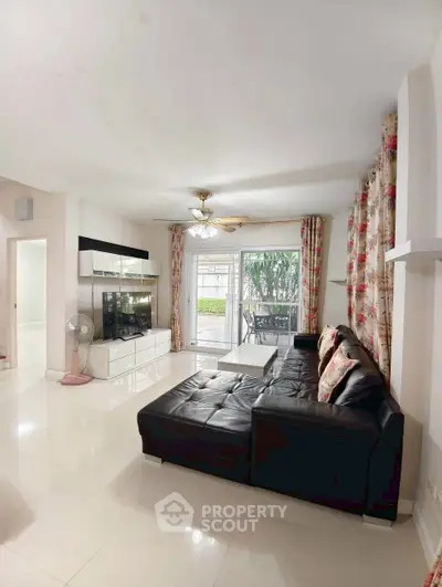 Spacious living room with modern decor and large black leather sofa