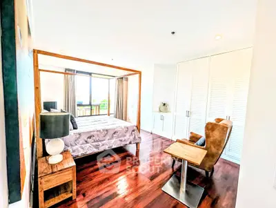 Spacious bedroom with elegant wooden flooring and large windows for natural light.