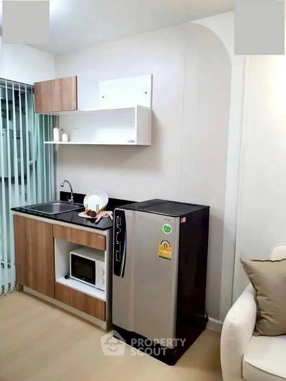 Modern compact kitchen with sleek fridge and microwave in stylish apartment.