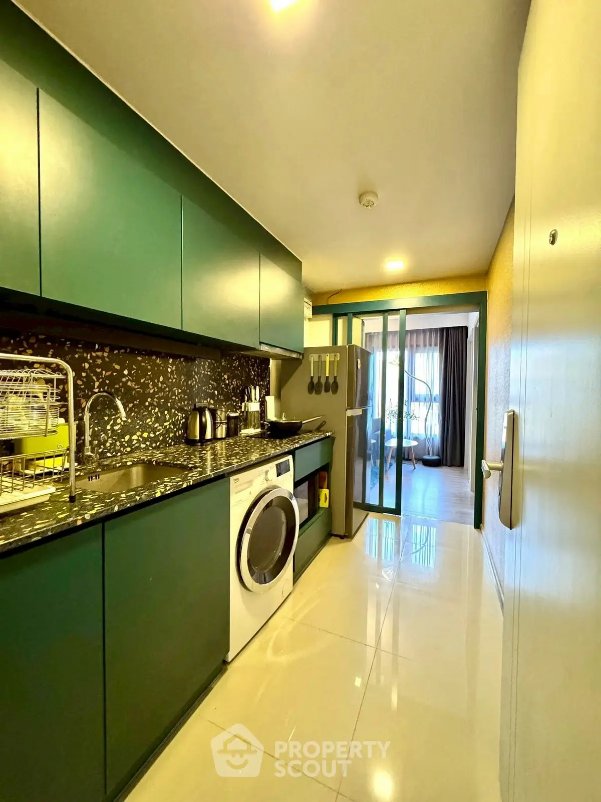 Modern kitchen with green cabinets and washing machine in sleek apartment