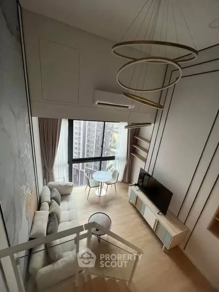 Modern loft-style living room with high ceilings and large windows offering city views.