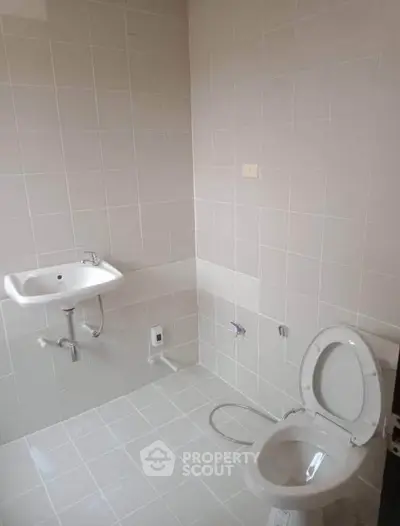 Minimalist bathroom with white tiles and basic fixtures, ideal for modern living spaces.