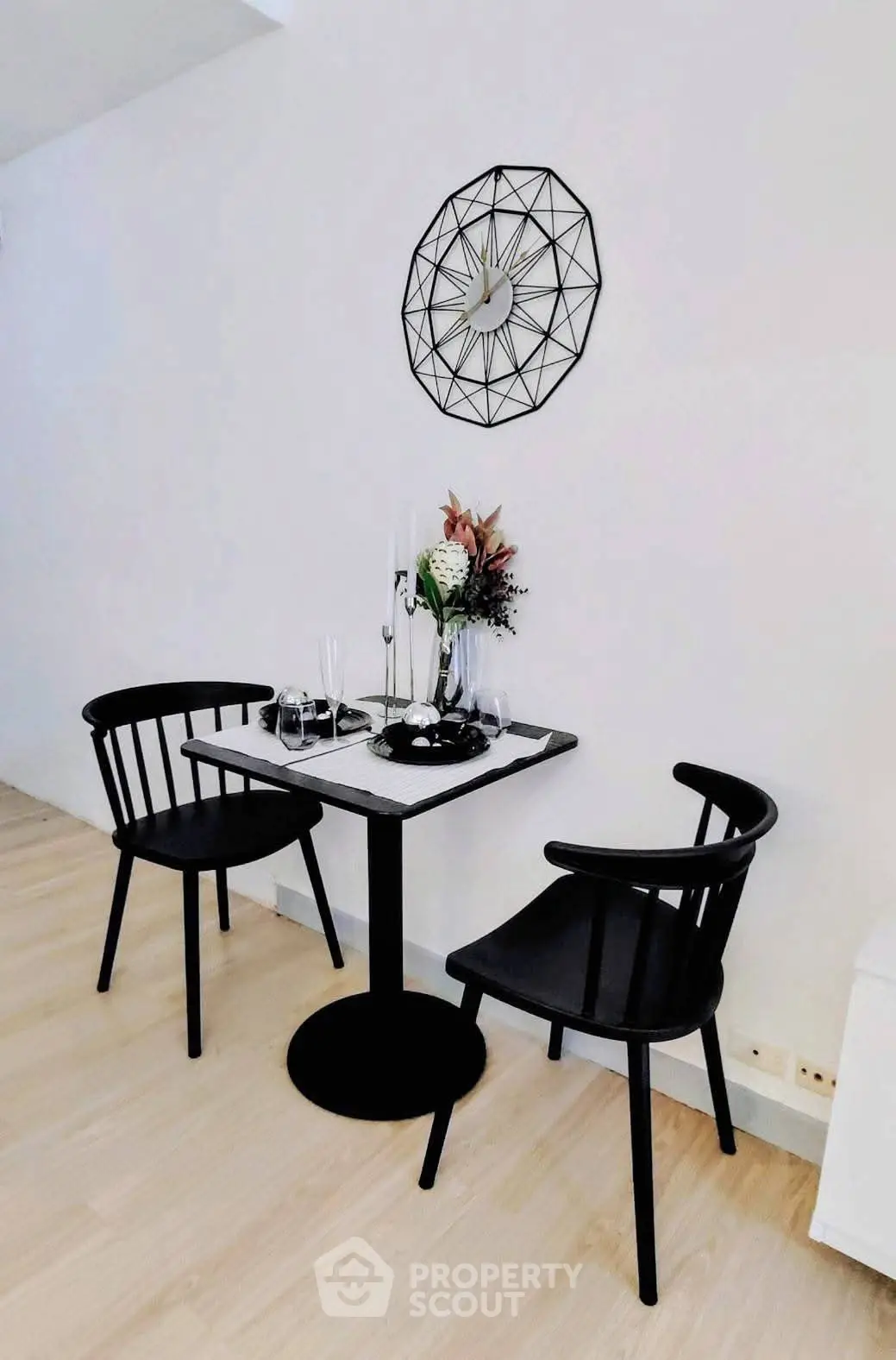 Stylish dining nook with modern black chairs and geometric wall art in a cozy apartment.
