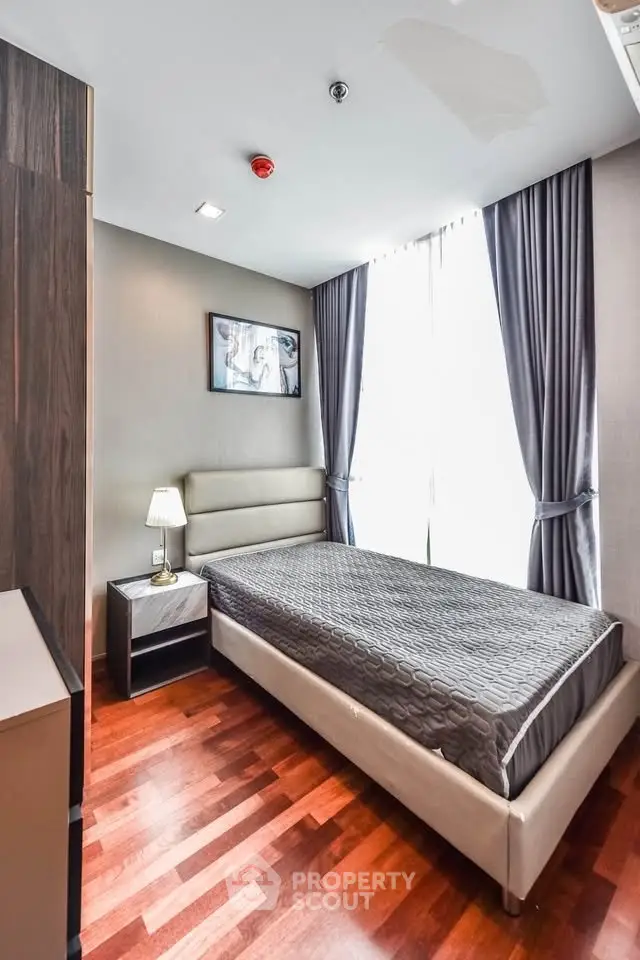 Modern bedroom with sleek design and natural light, featuring hardwood floors and elegant decor.