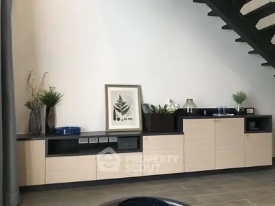 Stylish modern living room with sleek cabinetry and decorative accents under a staircase.