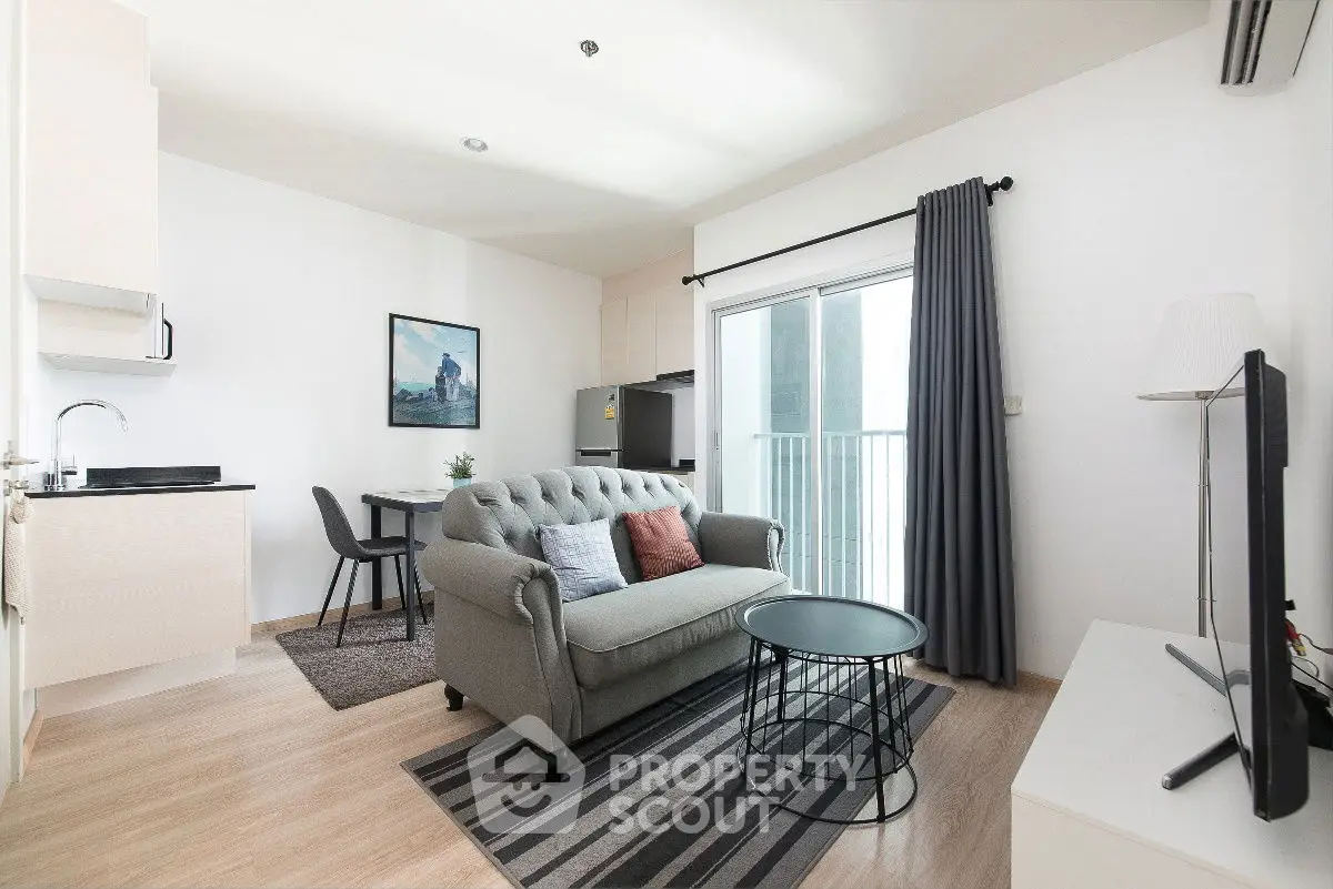 Modern living room with stylish sofa, open kitchen, and balcony access.