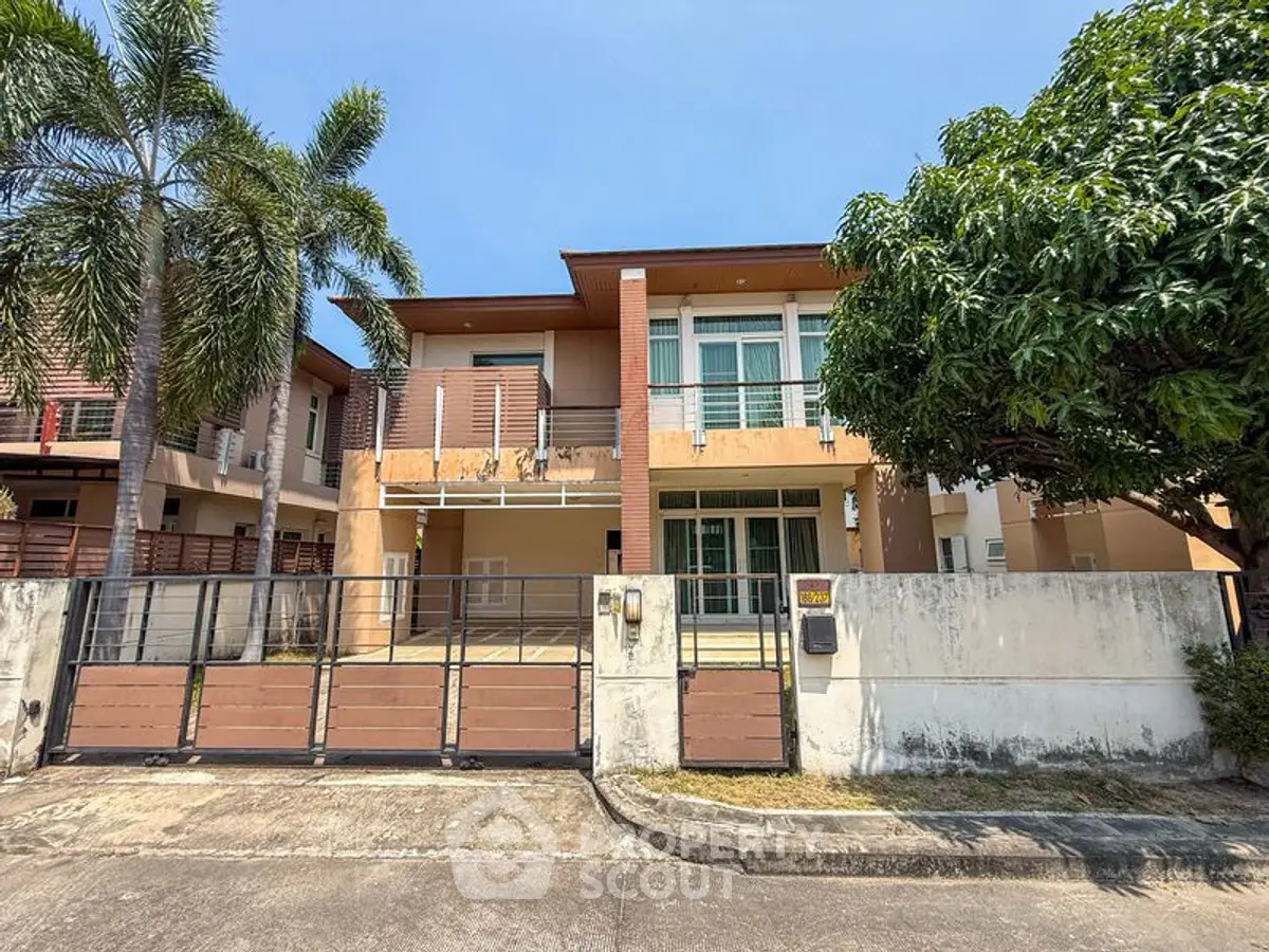 Modern two-story house with gated entrance and lush greenery