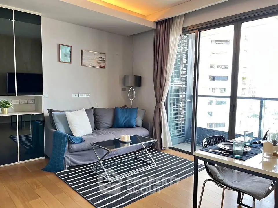 Modern living room with cozy sofa, stylish decor, and large balcony access in a high-rise apartment.