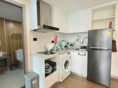 Modern kitchen with sleek appliances and adjacent bathroom in a compact apartment layout.