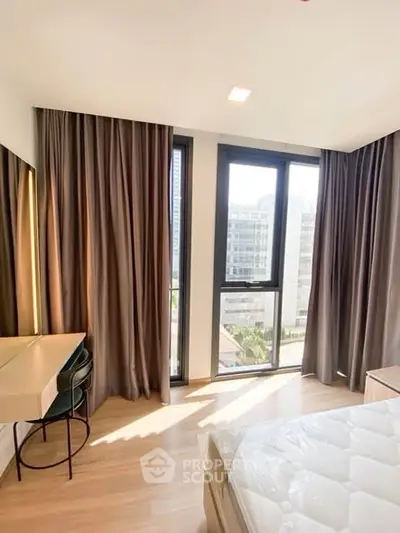 Bright bedroom with large windows and modern furnishings in a high-rise apartment.