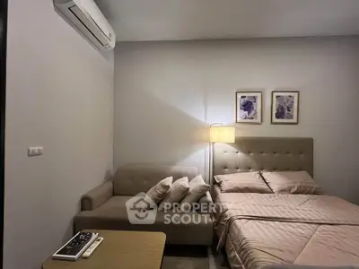 Cozy bedroom with modern decor, featuring a comfortable bed and stylish sofa under soft lighting.