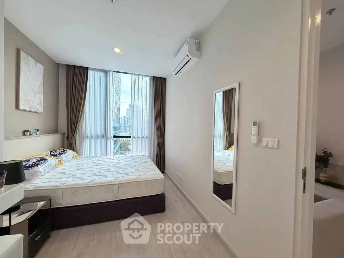 Modern bedroom with large window and stylish decor in a contemporary apartment.