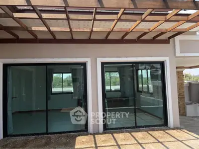 Modern patio with large glass doors and wooden pergola, offering seamless indoor-outdoor living.