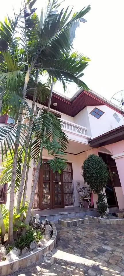 Charming two-story house with lush garden and elegant balcony, perfect for serene living.