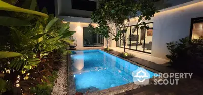 Luxurious modern home with illuminated private pool and lush garden at night