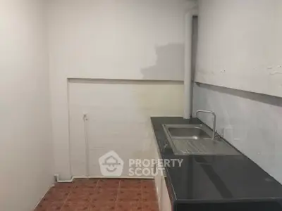Compact kitchen with sleek black countertop and stainless steel sink