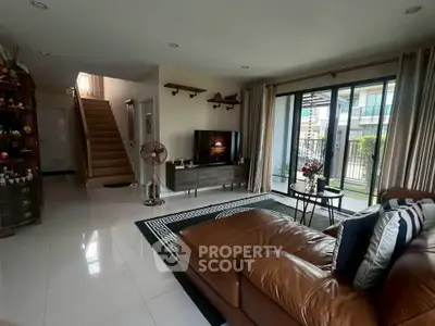 Spacious living room with modern decor and large windows opening to a balcony, perfect for relaxation.