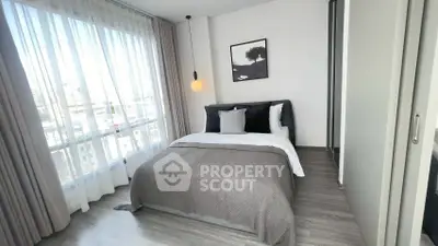 Modern bedroom with large window and stylish decor in urban apartment.