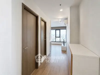 Spacious apartment hallway leading to a bright living area with city views.