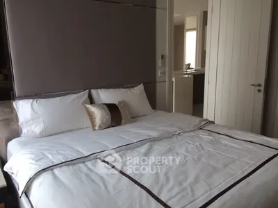 Modern bedroom with elegant bedding and neutral tones, featuring a glimpse into a stylish kitchen area.