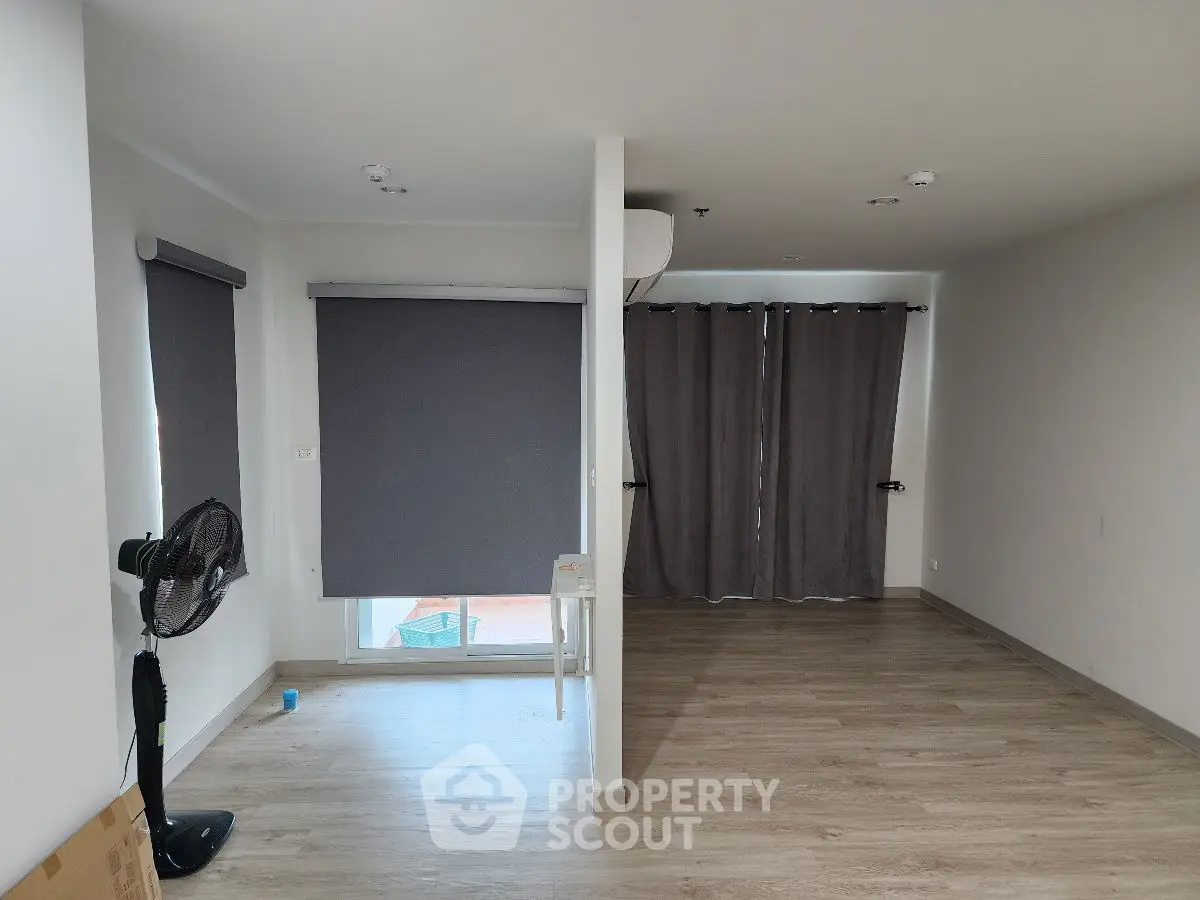 Spacious empty room with wooden flooring and large windows, ideal for customization.