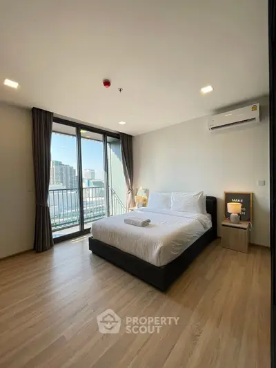Modern bedroom with city view and balcony access in high-rise apartment