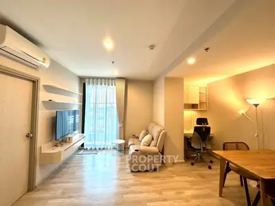 Modern living room with cozy seating and stylish decor, featuring a wall-mounted TV and natural light.