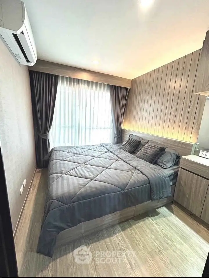 Modern bedroom with stylish wood paneling and cozy bedding in a well-lit apartment.