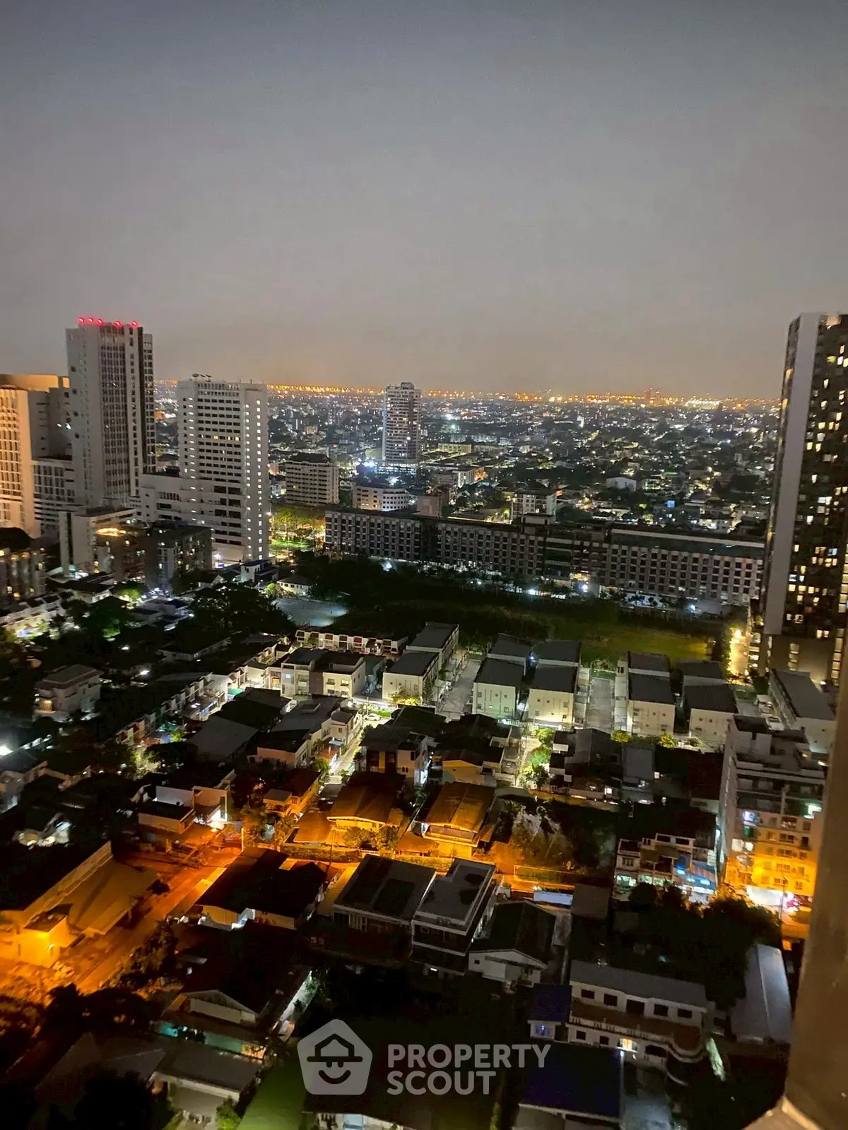 Stunning cityscape view from high-rise apartment at night, showcasing vibrant urban lights.