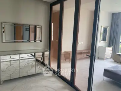 Elegant bedroom with mirrored dresser and large glass doors opening to a bright space.