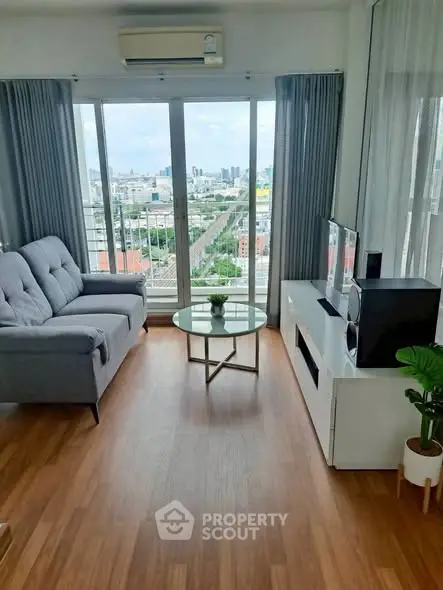 Modern living room with panoramic city view, featuring sleek furniture and wooden flooring.