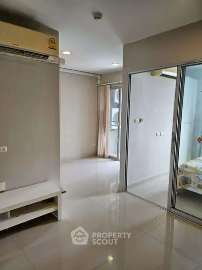 Modern apartment interior with sliding glass doors and air conditioning, featuring sleek flooring and neutral tones.