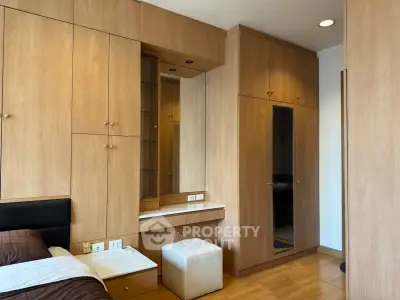 Spacious bedroom with elegant wooden cabinetry and cozy seating area.
