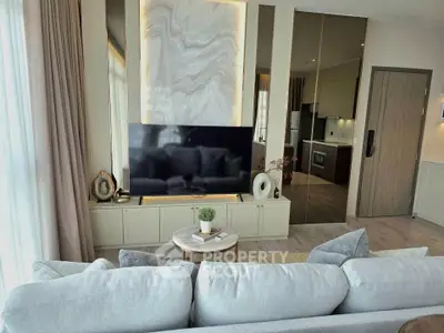 Luxurious living room with modern decor and open kitchen layout, featuring a large TV and elegant furnishings.