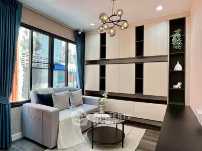 Stylish living room with modern chandelier and built-in shelving, perfect for cozy gatherings.