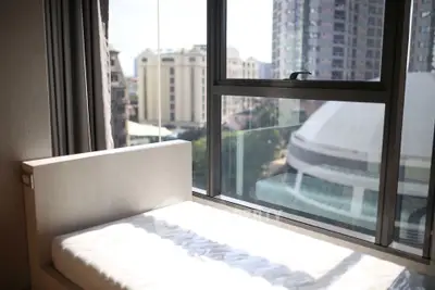 Bright bedroom with large window offering city view in modern apartment.